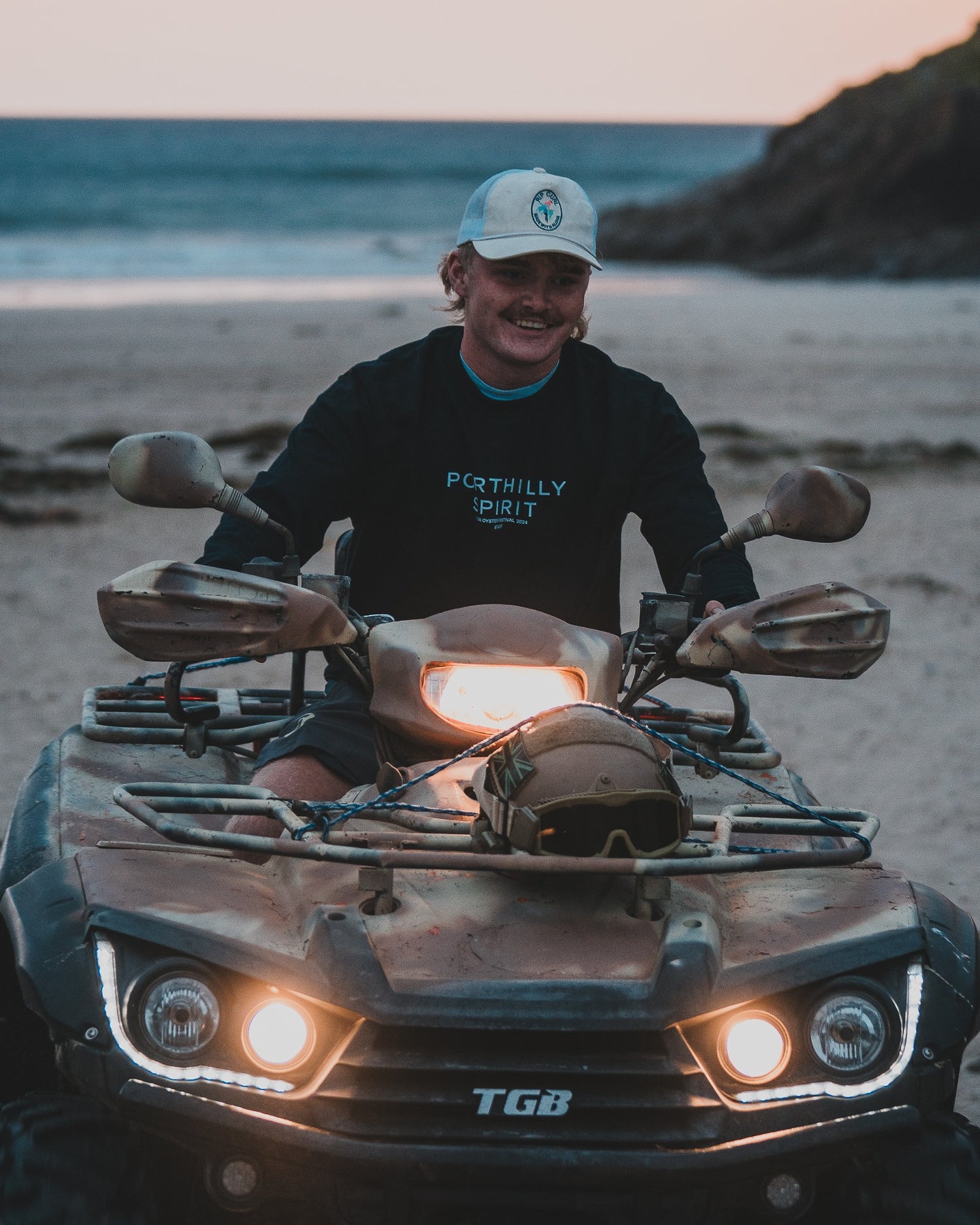 Navy Porthilly Spirit sweatshirt on a quad bike at sunset on the beach