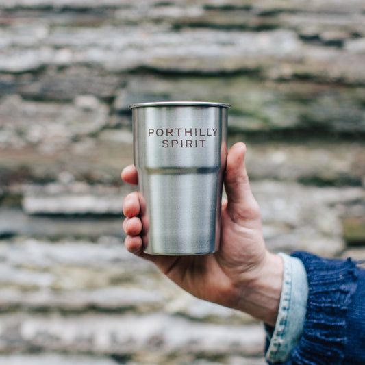 Hand holding a Porthilly Spirit steel pint cup against a slate wall